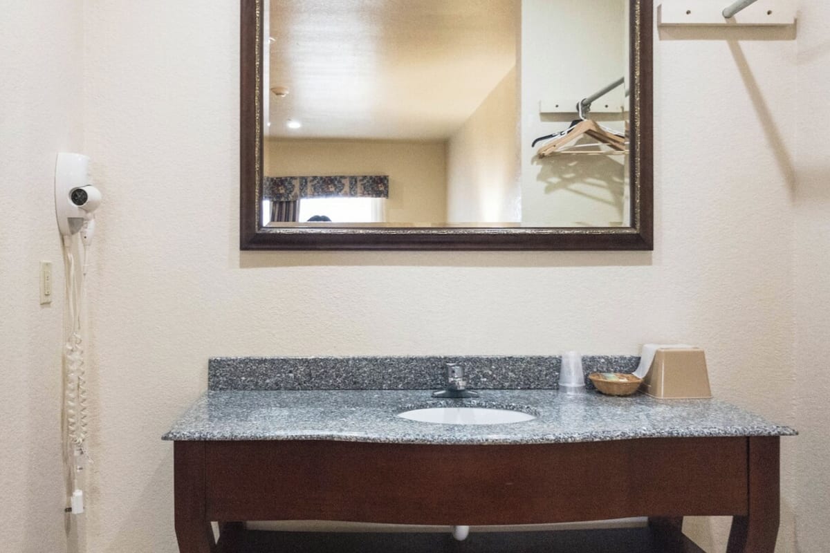A bathroom with a granite countertop sink, a mirror, and a towel rack.