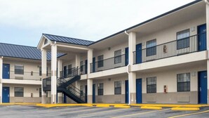 A multi-story motel with a central staircase, individual rooms with blue doors, and a parking lot. - Hiway Inn Express Of Coalgate (Coalgate)