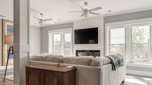 A living room with a sectional sofa, a wooden cabinet, a flat-screen TV, and a ceiling fan. - Downtown`s BEST LOFT ON THE SQUARE  `THE FIDDLE`!!! (Smithville)