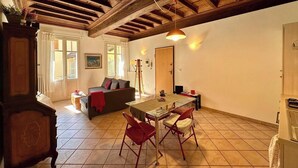 A spacious living area with a wooden ceiling, a dining table with chairs, a sofa, and a view of the outside through a window. - Don Bosco House (Chieri)