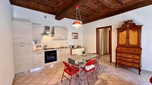 A kitchen with modern appliances, a dining table with red chairs, and a wooden cabinet. - Don Bosco House (Chieri)