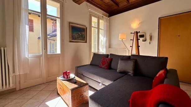 A cozy living room with a sofa, a wooden coffee table, and a red blanket. - Don Bosco House (Chieri)
