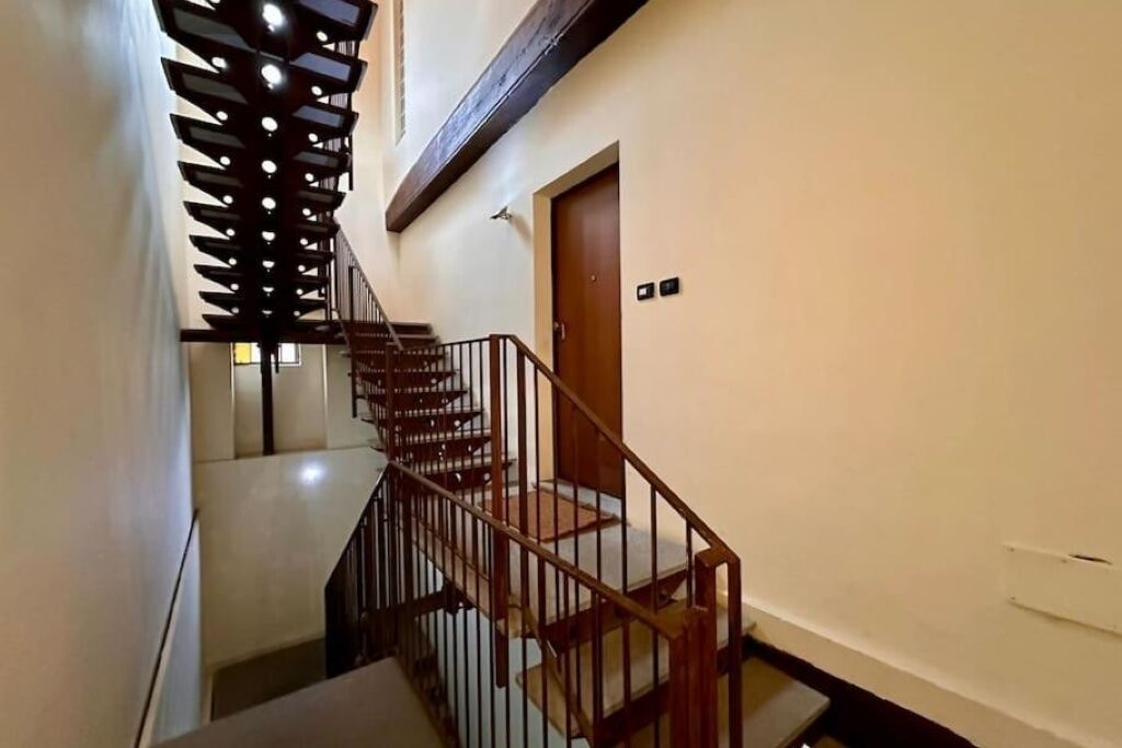 Una scala con ringhiera in legno e un moderno lampadario.