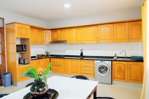 A compact kitchen with wooden cabinets, a microwave, a sink, and a washing machine.
