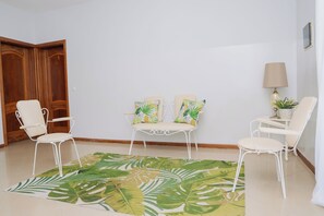 A room with a seating area consisting of two chairs and a small table, a patterned rug, and a lamp.