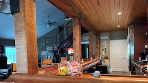Zona de bar con barra, ventilador de techo y vista del comedor al fondo.
