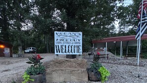 A welcome sign for Hoban's Hideout with a gravel ground and potted plants. - Hogan's Hideout Cottage #7 (Eminence)