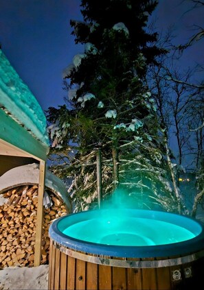 Un jacuzzi rodeado de árboles cubiertos de nieve y una estructura de madera.