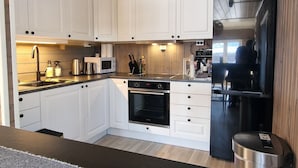 Una cucina moderna con mobili bianchi, elettrodomestici in acciaio inossidabile e soffitto in legno.