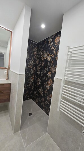 A bathroom with a shower, a mirror, and a towel rack.