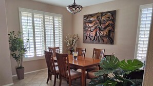 A dining area with a wooden table and chairs, a potted plant, and a wall-mounted artwork. - Anthem Family getaway (Anthem)