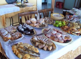 Una mesa de buffet con diferentes opciones de comida, incluyendo pasteles, frutas y postres.