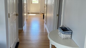 A hallway with wooden flooring, white doors, and a small table with a basket.
