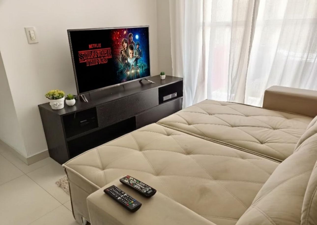 Une chambre à coucher avec un lit, un téléviseur posé sur un meuble et deux télécommandes sur le lit.