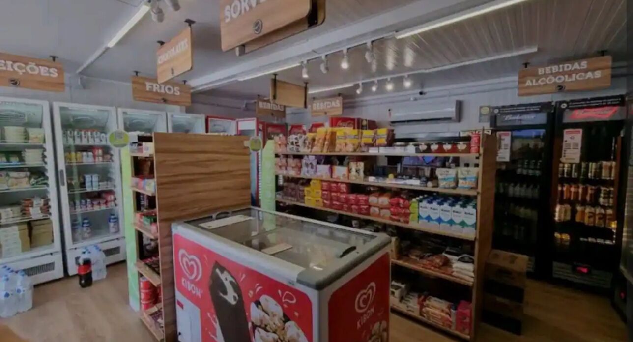A grocery store with refrigerated sections, shelves stocked with various products, and signs indicating different sections like 'FRIOS' and 'BEBIDAS ALCOÓLICAS'.
