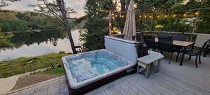 Un bain à remous sur une terrasse en bois, avec des sièges d’extérieur et une vue sur un lac.