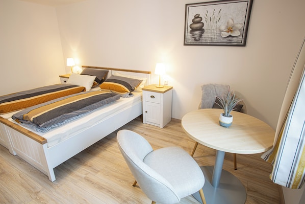A neatly arranged bedroom with a bed, bedside tables with lamps, a chair, and a small round table with a plant. - Neu Saniertes Ferienhaus Umgeben von Malerischen Wiesen (Surberg)