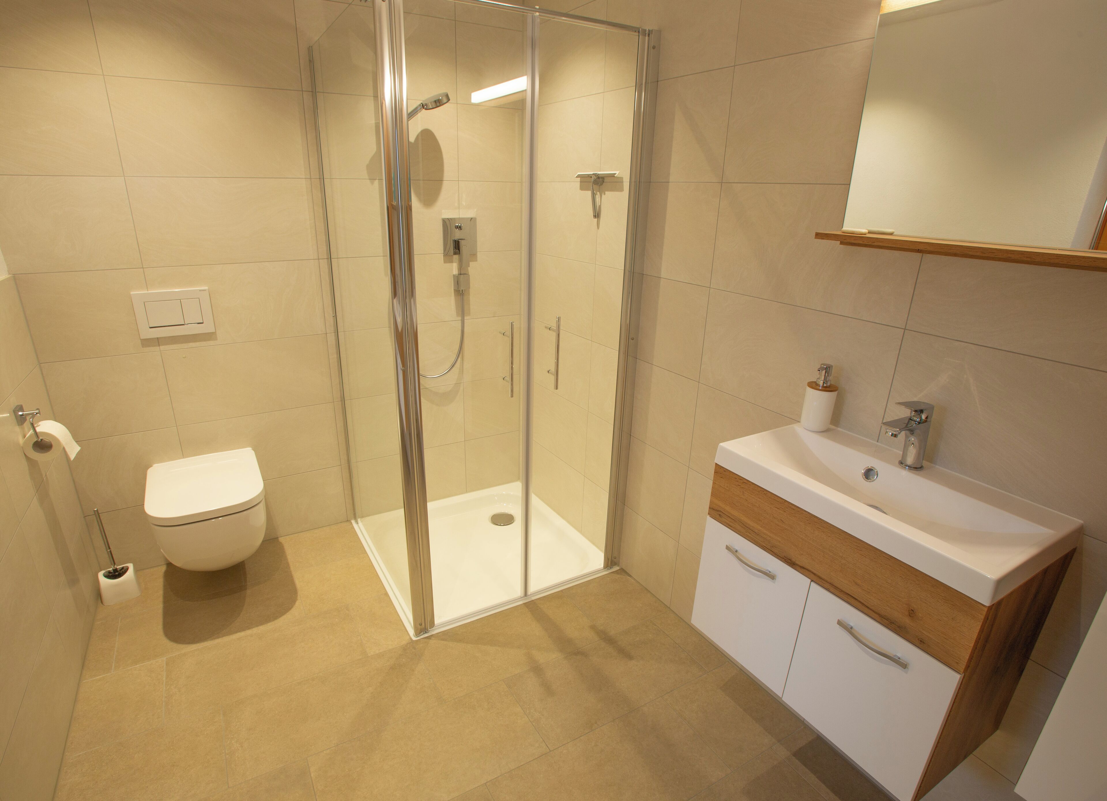 Une salle de bain moderne avec une douche à parois de verre, des toilettes blanches et un lavabo agrémenté de touches de bois.