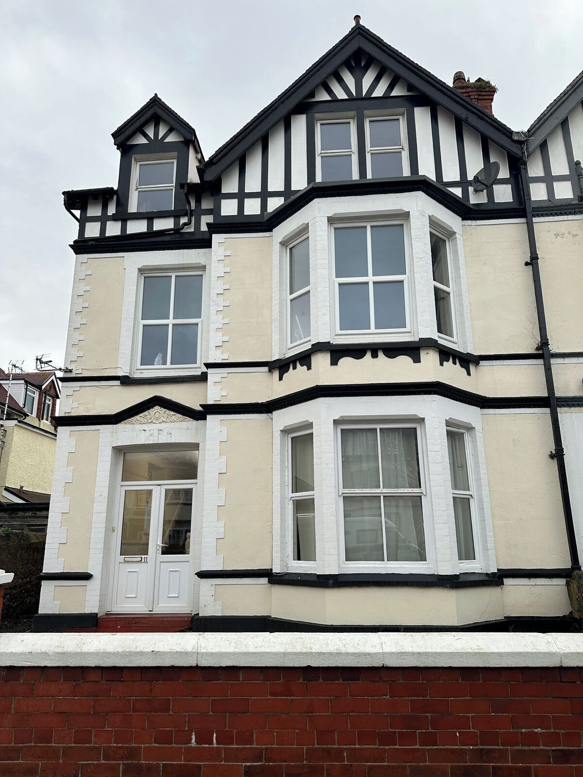 A two-story building with a bay window, a door, and a chimney.