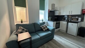A modern kitchen with white cabinets, a microwave, and a small refrigerator. - Carmen Sylva Holiday let Llandudno sea front (Llandudno)