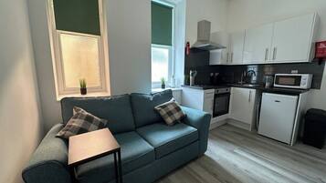 A modern kitchen with white cabinets, a microwave, and a small refrigerator.