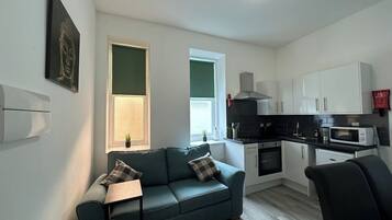 A compact living space with a kitchenette, a sofa, and a dining area.