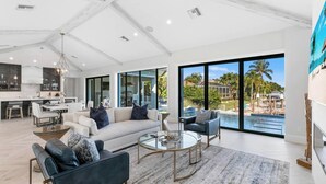 A spacious living area with a large sofa, a coffee table, and a view of a pool and outdoor area. - Bella Fratelli Marco Island 🏝️
With Electric Lift Pier (Marco Island)