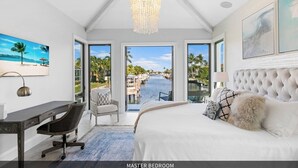 A master bedroom with a large bed, a desk, a chair, and a view of a pool and beach. - Bella Fratelli Marco Island 🏝️
With Electric Lift Pier (Marco Island)