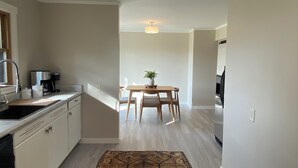 Una cocina moderna con comedor, piso de madera clara y una mesa central con sillas.