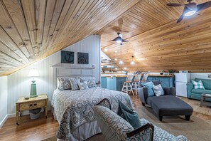 Een ruime loft slaapkamer met een groot bed, een bureau en een kitchenette.