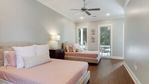Ein Schlafzimmer mit zwei Betten, einem Deckenventilator und einem Balkon mit Jalousien.