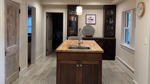 A modern kitchen with a central island, wooden cabinets, and a pendant light.