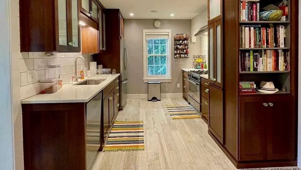 A kitchen with wooden cabinets, a central island, and a bookshelf filled with books.