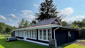 A building with a long side window, a garage door, and a barrel.