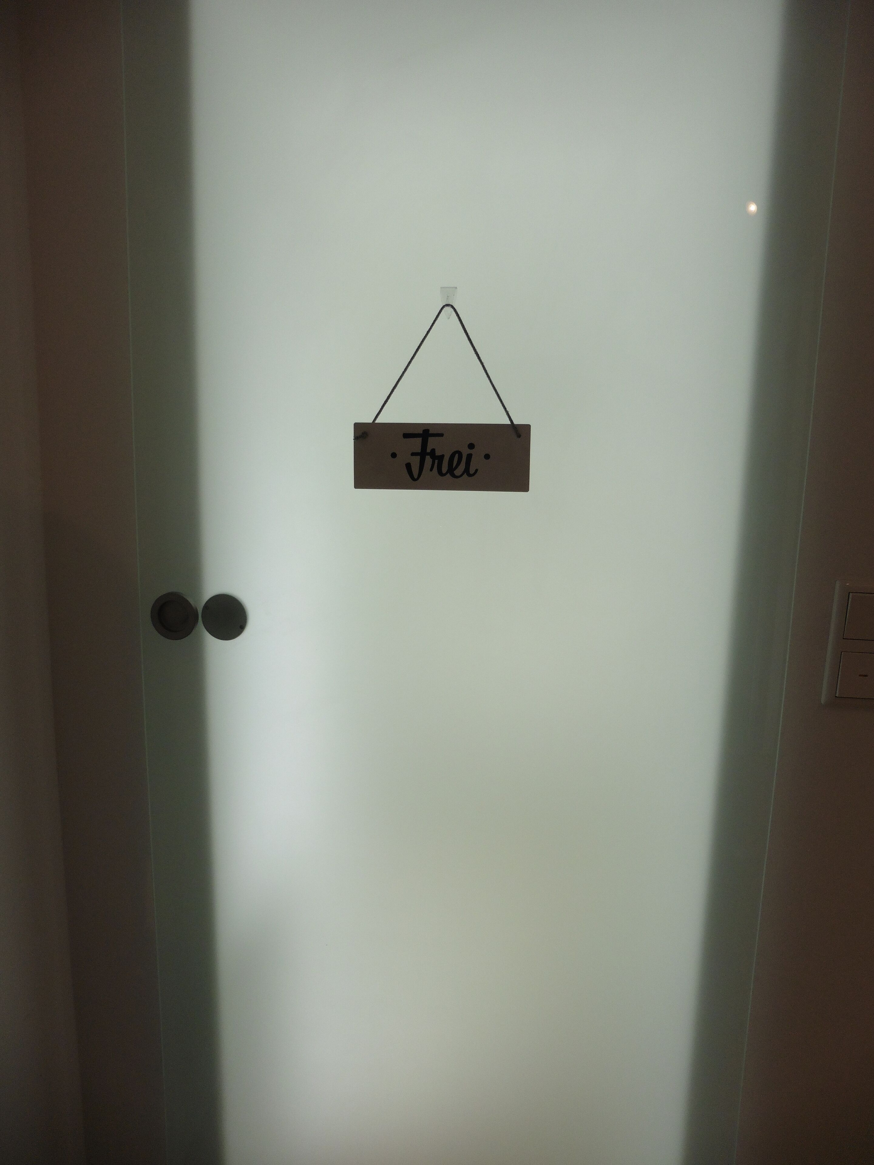 Une porte en verre dépoli sur laquelle est accrochée une enseigne portant le nom « Frei ».