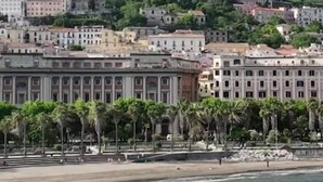 Una cittadina costiera con edifici su una collina, una spiaggia e un tratto d'acqua.