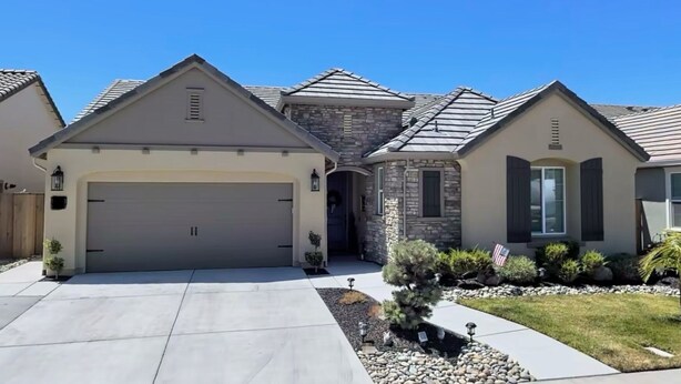 A suburban house with a garage, stone facade, and a well-maintained lawn. - Lovely Home in Lodi (Lodi)