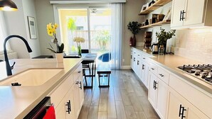 A modern kitchen with white cabinets, a wooden floor, and a central island. - Lovely Home in Lodi (Lodi)