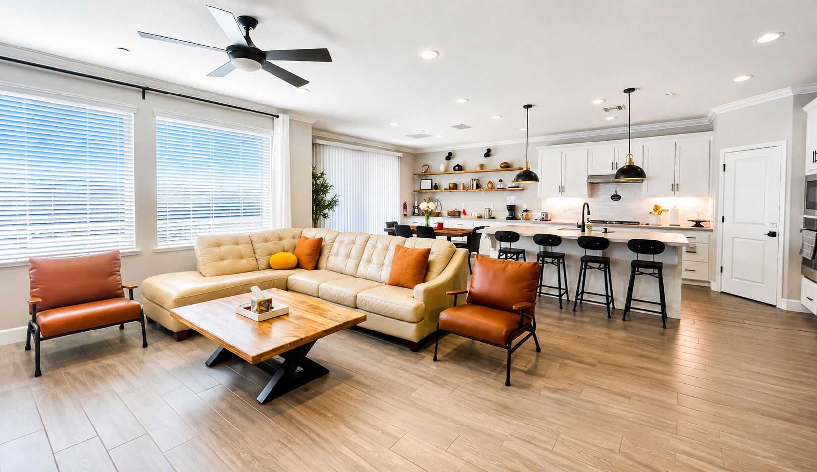 A modern living room with a sofa, chairs, a coffee table, and a kitchen area with bar stools.