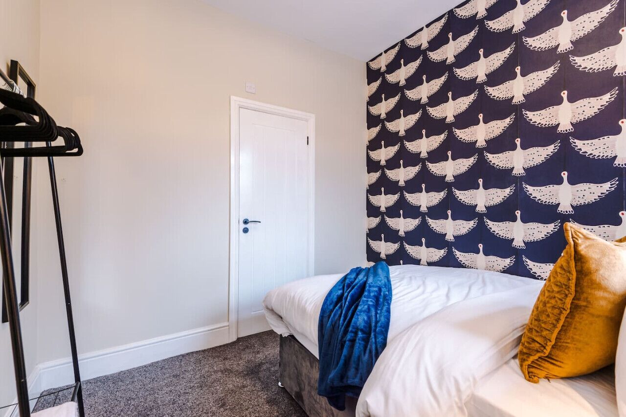 Una camera da letto con un letto, una porta, un appendiabiti e una parete decorata.
