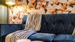 A dark blue sofa with a tufted backrest and a draped throw blanket. - Salford Sanctuary 5 Bed House (Salford)