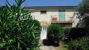 A house with a white door, green shutters, and a small balcony with a red chair. - Proche Mer, Appartement Classé 2 Dans Petite Résidence (Santa-Lucia-di-Moriani)