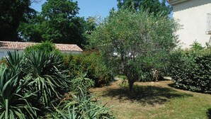 A garden with various plants and a building with a tiled roof. - Proche Mer, Appartement Classé 2 Dans Petite Résidence (Santa-Lucia-di-Moriani)