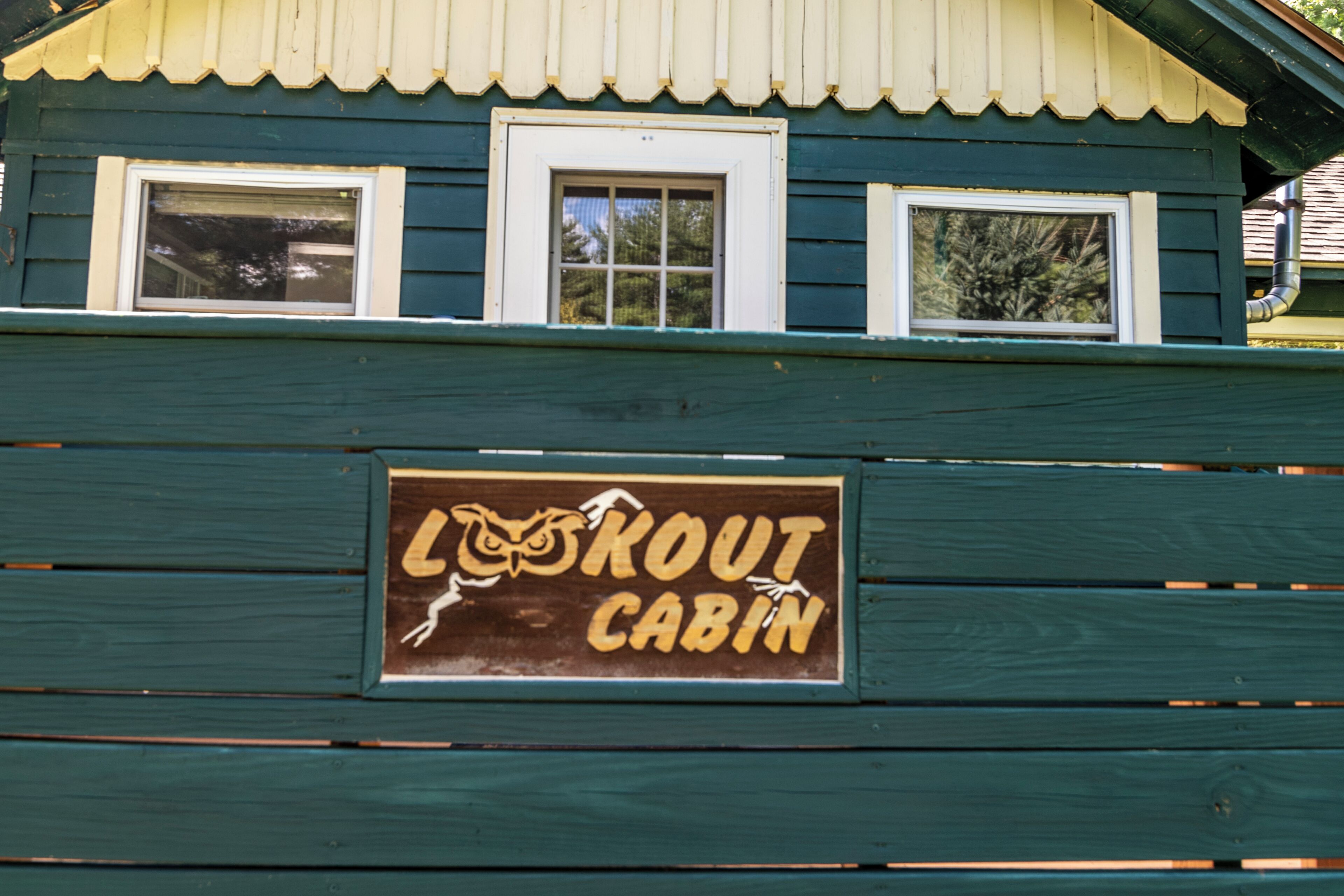 Een houten hutje met een bord waarop staat 'Lout Cabin'.