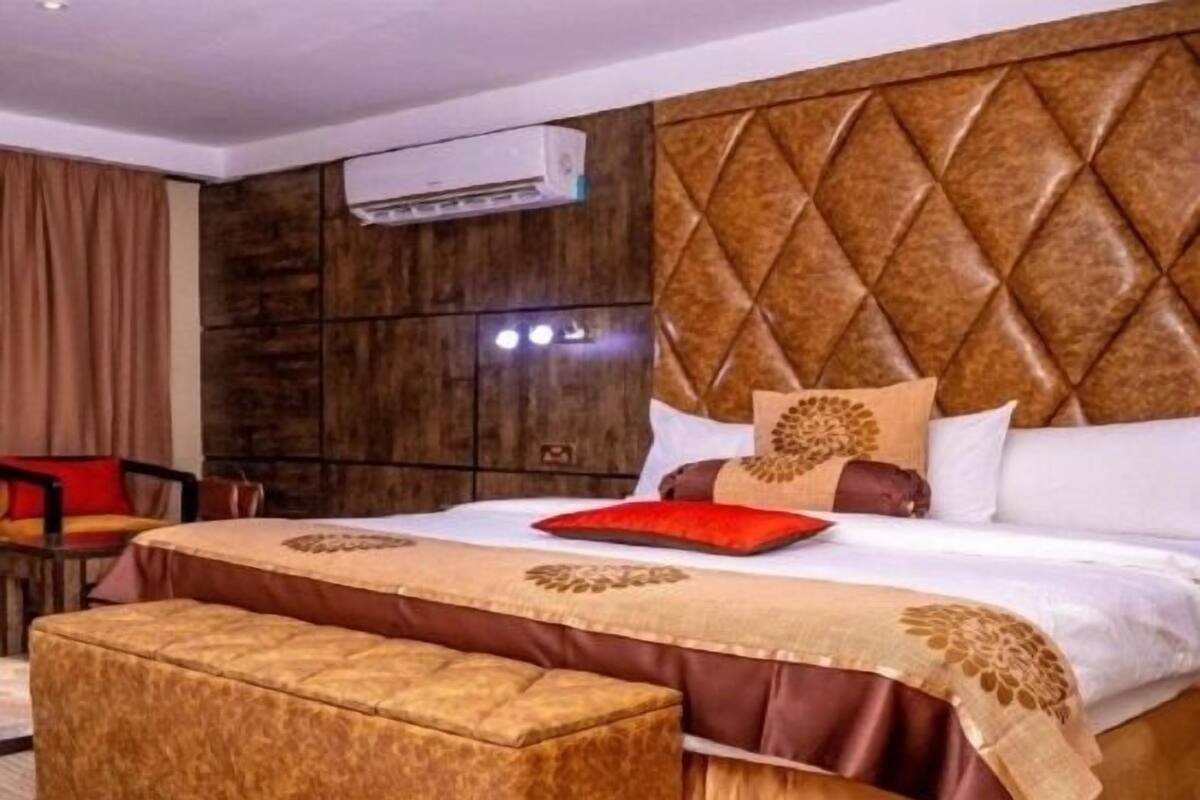 Una habitación de hotel con una cama grande, un cabecero de madera, una silla roja y una mesita.