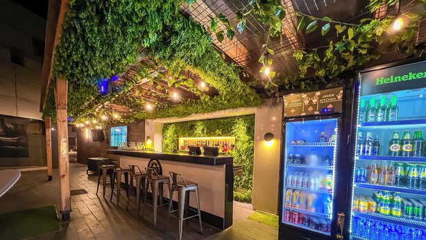 A bar area with a seating arrangement and a Heineken refrigerator.