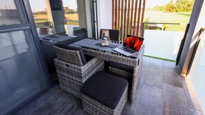 Un balcone con mobili in vimini, un laptop e un vasetto con delle pietre.