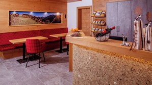 A wooden interior with a wooden bench, a table, and a shelf with books and a wine bottle. - Apart Darre (Serfaus)