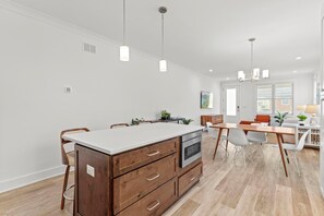 Una cocina moderna con una isla central, armarios de madera e iluminación colgante.