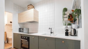 A modern kitchen with white tiles, a built-in oven, a microwave, and a kettle on the countertop. - T2 Tout Confort - Central- Bord de mer 100m - Clim (La Ciotat)
